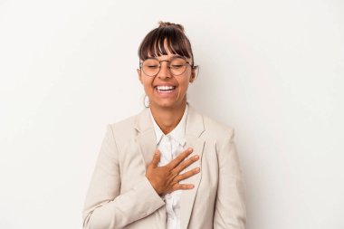 Beyaz arka planda soyutlanmış genç bir ırk kadını yüksek sesle gülüyor ve elini göğsüne koyuyor..