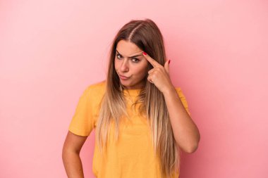 Pembe arka planda izole edilmiş, hoşnutsuzca kaşlarını çatmış, kollarını kavuşturmuş genç bir Rus kadın..