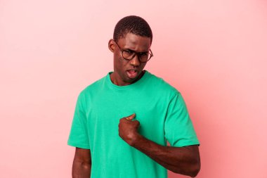 Pembe arka planda izole edilmiş genç Afro-Amerikalı adam parmağını göstererek şaşırdı ve gülümsedi..