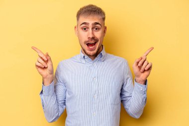 Sarı arka planda izole edilmiş genç beyaz adam farklı kopya alanlarını gösteriyor, birini seçiyor, parmağıyla gösteriyor..