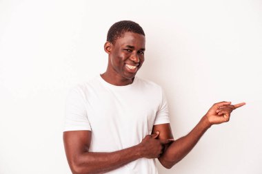Beyaz arka planda izole edilmiş genç bir Afrikalı Amerikalı işaret parmağıyla işaret ederek gülümsüyor..