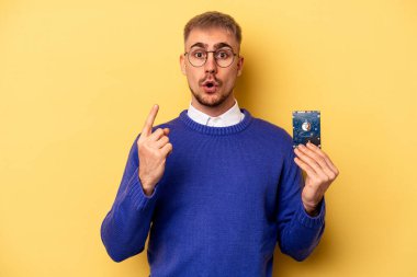 Genç bilgisayarcı sarı arka planda izole edildi. Yaratıcılık kavramı, harika bir fikri var..