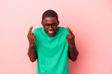 Genç Afrikalı Amerikalı adam pembe arka planda izole edilmiş şans diliyor.