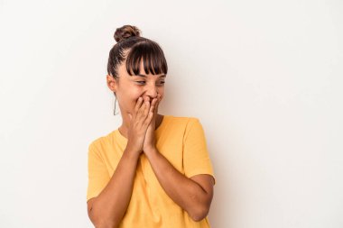 Beyaz arka planda izole edilmiş genç bir ırk kadını bir şeye gülüyor, elleriyle ağzını kapatıyor..