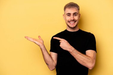 Sarı arka planda izole edilmiş genç beyaz bir adam, elinde bir fotokopi alanı tutarken heyecanlanıyor..