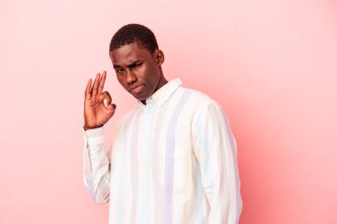 Genç Afro-Amerikalı bir adam pembe arka planda izole edilmiş bir şekilde göz açıp kapayıncaya kadar iyi bir jest yapıyor..