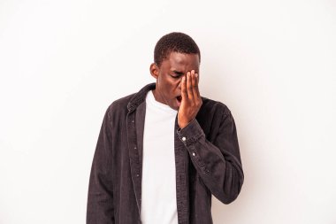 Beyaz arka planda izole edilmiş genç Afrikalı Amerikalı adam esniyor. Ağzını eliyle kapatan yorgun bir hareket sergiliyor..