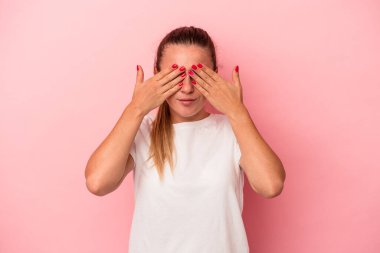 Pembe arka planda izole edilmiş genç Rus kadın elleriyle gözlerini kapatmaktan korkuyor..