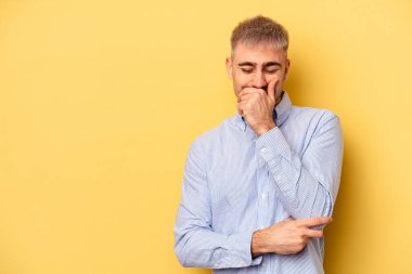 Sarı arka planda izole edilmiş genç beyaz adam gülüyor, kaygısız, doğal duygu..