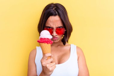 Sarı arka planda izole edilmiş dondurma tutan melez bir kadın.