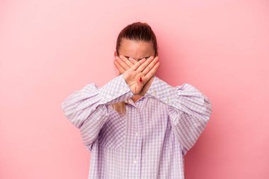 Pembe arka planda izole edilmiş genç bir Rus kadın kollarıyla ölçek oluşturuyor, mutlu ve kendinden emin hissediyor..