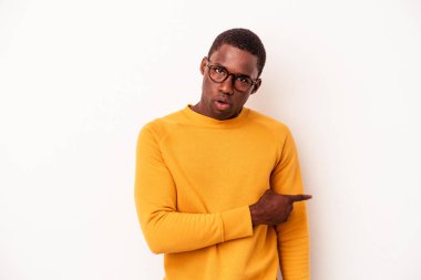 Beyaz arka planda izole edilmiş genç Afrikalı Amerikalı adam gülümsüyor ve boş alanda bir şeyler gösteriyor..