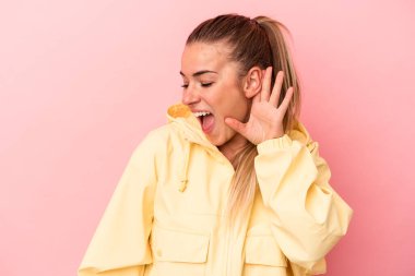 Pembe arka planda izole edilmiş genç Rus kadın bir dedikoduyu dinlemeye çalışıyor..