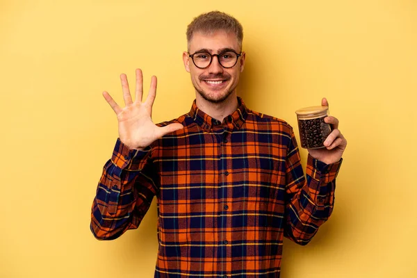 Young Caucasian Man Holding Coffee Jar Isolated Yellow Background Smiling — Photo