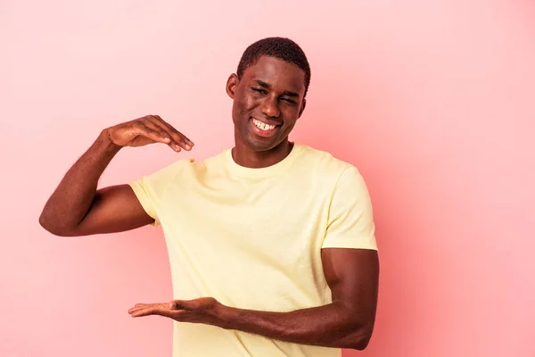 Jovem Afro Americano Isolado Fundo Rosa Segurando Algo Pouco Com — Fotografia de Stock