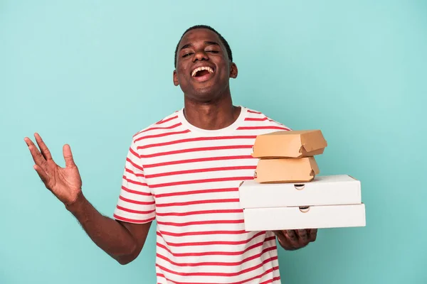 Mladý Afroameričan Drží Pizzy Hamburgery Izolované Modrém Pozadí Obdrží Příjemné — Stock fotografie