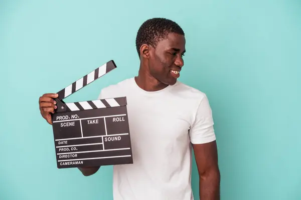 Jonge Afro Amerikaanse Man Houdt Clapperboard Geïsoleerd Blauwe Achtergrond Kijkt — Stockfoto