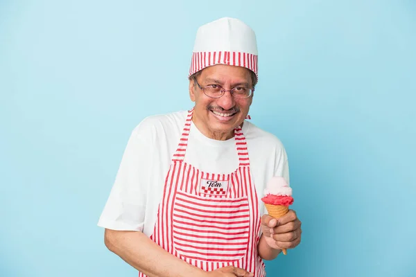 Senior american ice cream man holding an ice cream isolated on blue background laughing and having fun.