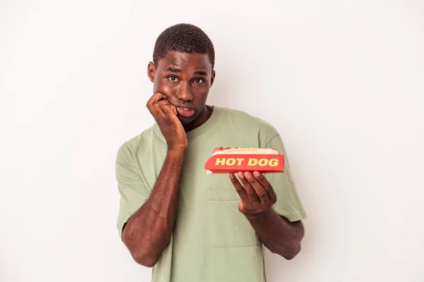 Młody Afroamerykanin Jedzący Hot Doga Białym Tle Obgryzający Paznokcie Nerwowy — Zdjęcie stockowe