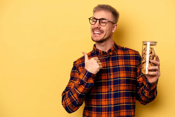 Young Caucasian Man Holding Cookies Jar Isolated Yellow Background Points — Stock fotografie