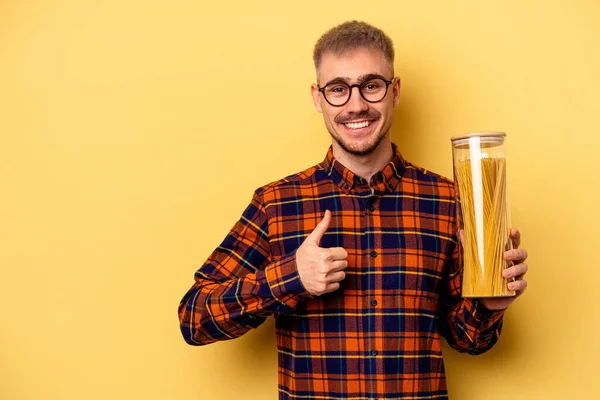 Young Caucasian Man Holding Spaghettis Jar Isolated Yellow Background Smiling — Fotografia de Stock
