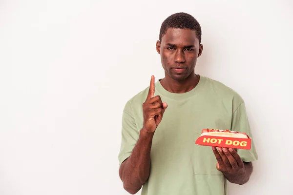 Młody Afroamerykanin Jedzący Hot Doga Białym Tle Pokazuje Numer Jeden — Zdjęcie stockowe