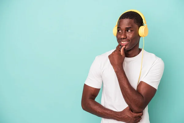 青い背景に囲まれた音楽を聴いている若いアフリカ系アメリカ人の男性は コピースペースを見る何かについてリラックスした考え — ストック写真