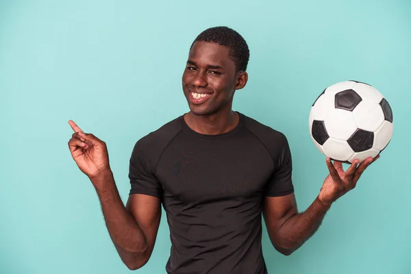 Giovane Uomo Afroamericano Giocare Calcio Isolato Sfondo Blu Sorridente Indicando — Foto Stock