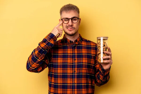 Junger Kaukasischer Mann Hält Plätzchenglas Isoliert Auf Gelbem Hintergrund Und — Stockfoto