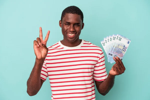 Mladý Afroameričan Drží Bankovky Izolované Modrém Pozadí Ukazující Číslo Dvě — Stock fotografie