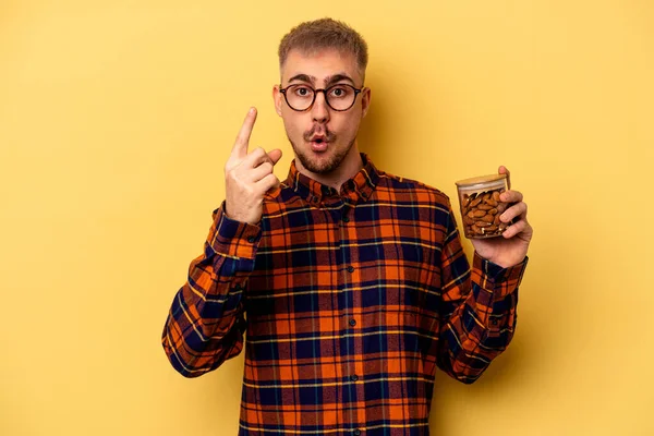 Young Caucasian Man Holding Almond Jar Isolated Yellow Background Having — Stockfoto