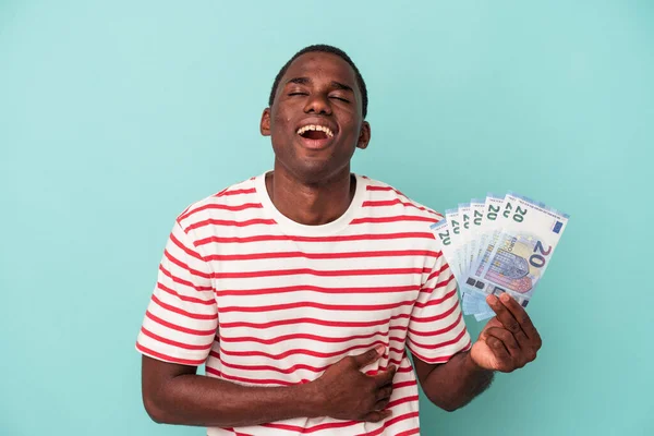 Młody Afroamerykanin Trzyma Banknoty Odizolowane Niebieskim Tle Śmiejąc Się Bawiąc — Zdjęcie stockowe