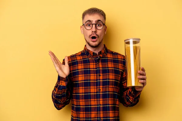 Young Caucasian Man Holding Spaghettis Jar Isolated Yellow Background Surprised —  Fotos de Stock