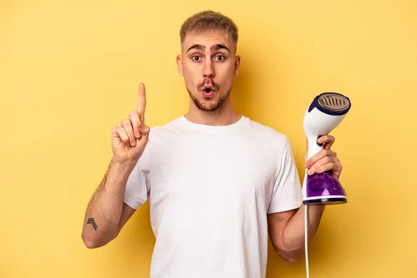 Young Caucasian Man Holding Iron Isolated Yellow Background Having Some — 图库照片
