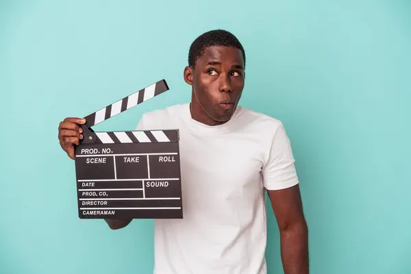 Young African American Man Holding Clapperboard Isolated Blue Background Shrugs — Stock Photo, Image