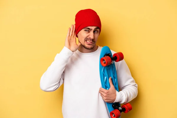 Young Skater Caucasian Man Isolated Yellow Background Trying Listening Gossip — Stok fotoğraf