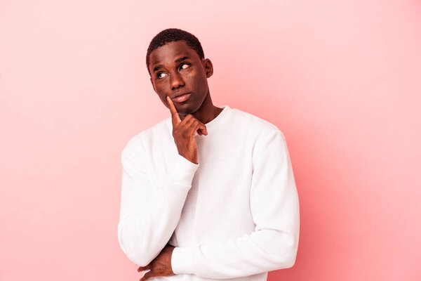 Young African American man isolated on pink background contemplating, planning a strategy, thinking about the way of a business.