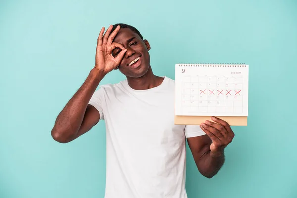 Jonge Afro Amerikaanse Man Met Een Kalender Geïsoleerd Blauwe Achtergrond — Stockfoto