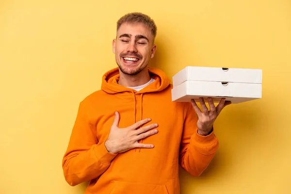 Young Caucasian Man Holding Pizzas Isolated Yellow Background Laughs Out — Stockfoto