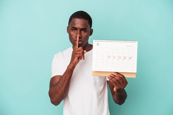 Mladý Afroameričan Drží Kalendář Izolovaný Modrém Pozadí Držet Tajemství Nebo — Stock fotografie