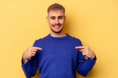 Sarı arka planda izole edilmiş genç beyaz adam parmakları aşağıda, olumlu bir his var..