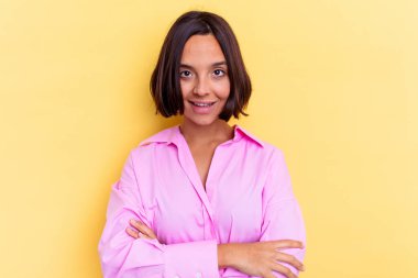 Sarı arka planda yaşayan genç melez kadın gülüyor ve eğleniyor..