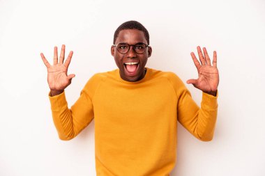 Beyaz arka planda izole edilmiş genç Afrikalı Amerikalı hoş bir sürpriz alıyor, heyecanlı ve el kaldırıyor..