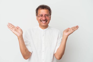 Middle aged indian man isolated on white background makes scale with arms, feels happy and confident.