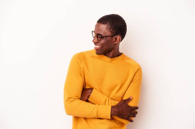 Beyaz arka planda izole edilmiş genç Afro-Amerikalı adam kollarını kavuşturarak gülümsüyor..