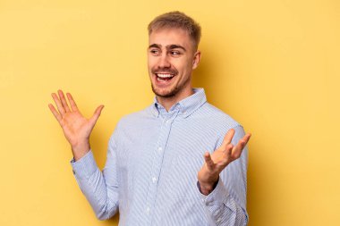 Sarı arka planda izole edilmiş genç beyaz bir adam neşeli bir şekilde gülüyor. Mutluluk kavramı.