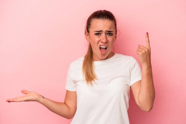 Pembe arka planda izole edilmiş genç bir Rus kadın elinde bir ürün tutuyor..