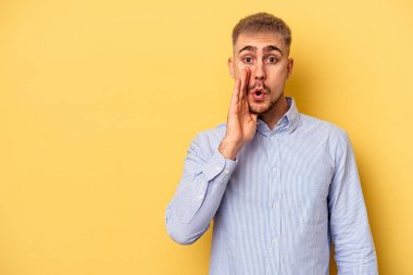 Sarı arka planda izole edilmiş genç beyaz bir adam gizli bir sıcak fren haberi veriyor ve yana bakıyor.