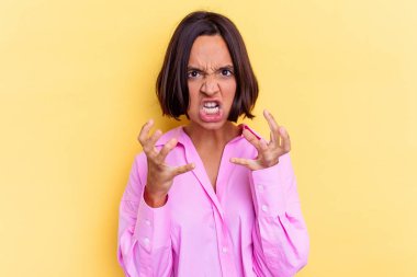Sarı arka planda izole edilmiş genç melez kadın gergin ellerle çığlık atıyor..