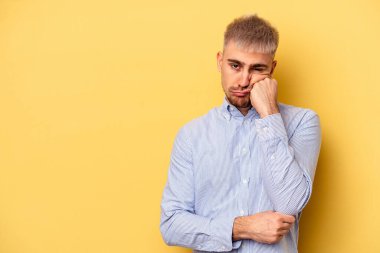Sarı arka planda izole edilmiş genç, üzgün ve dalgın hisseden, kopyalama alanına bakan beyaz bir adam..